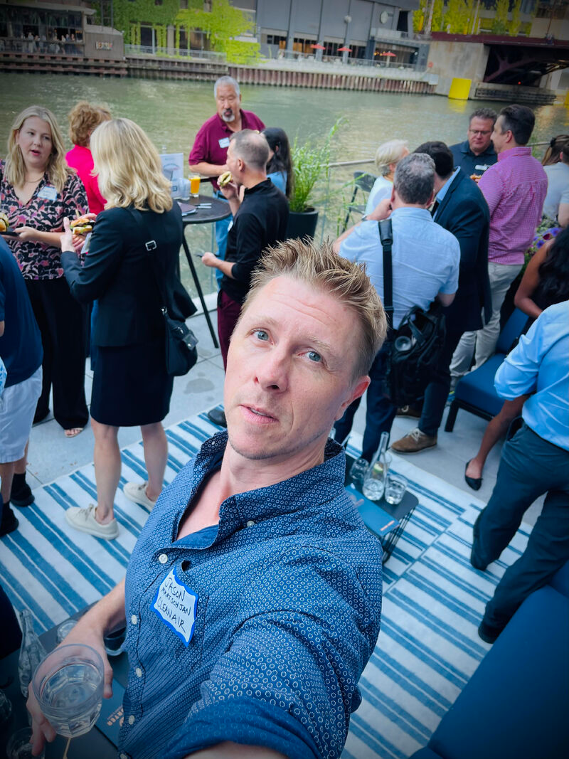 A man takes a selfie at a crowded indoor networking event