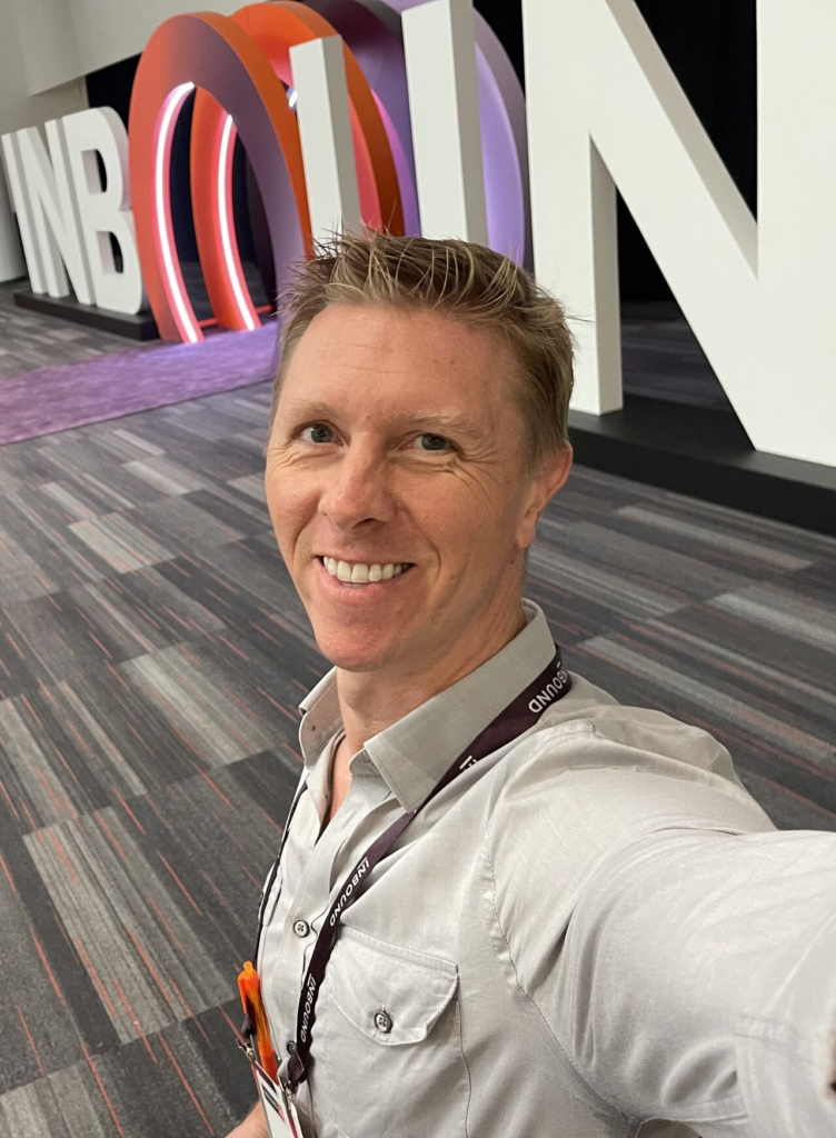 A smiling man takes a selfie in front of giant INBOUND letters