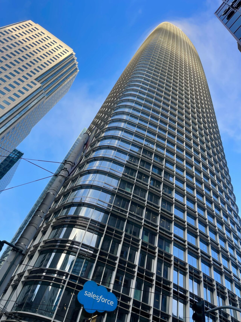 Looking straight up a tapering glass skyscraper against a blue sky