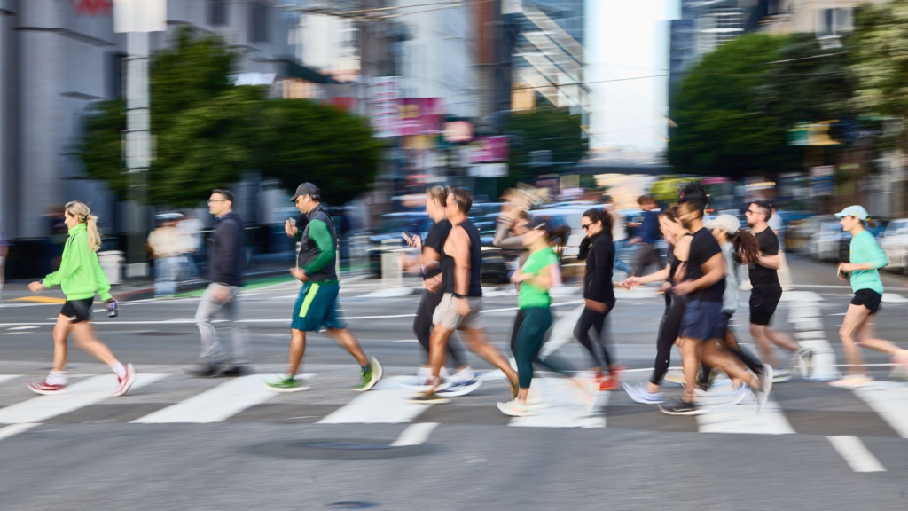 A group of runners crossing a city street in the morning